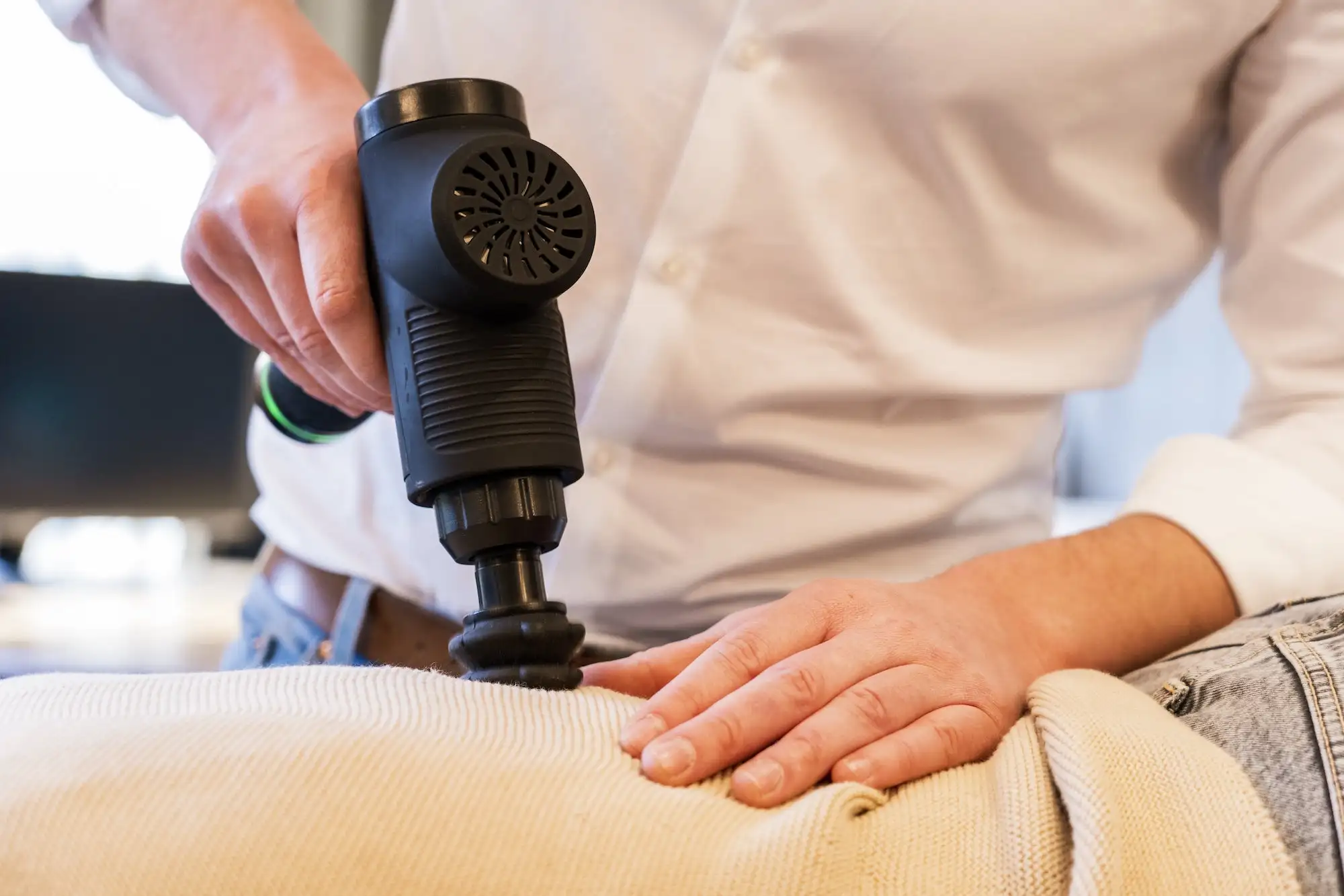 De chiropractor behandled een patient zijn run met een massage gun